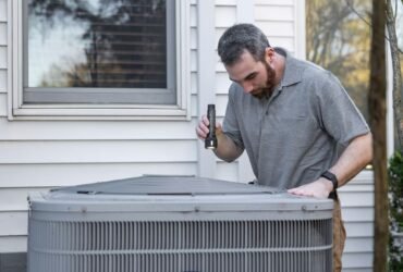 Technician inspecting an outdoor HVAC unit for maintenance.